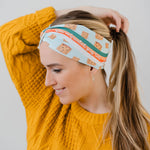 Women wearing the Unfrosted Poptart light blue headband with a wavy rainbow of teal, orange and coral and unfrosted pop-tarts with the words "you unfrosted pop-tart" in cursive