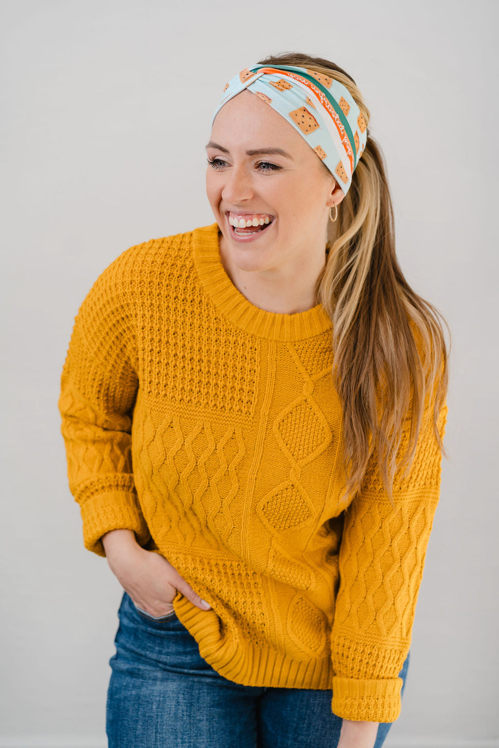 Women wearing the Unfrosted Poptart light blue headband with a wavy rainbow of teal, orange and coral and unfrosted pop-tarts with the words "you unfrosted pop-tart" in cursive