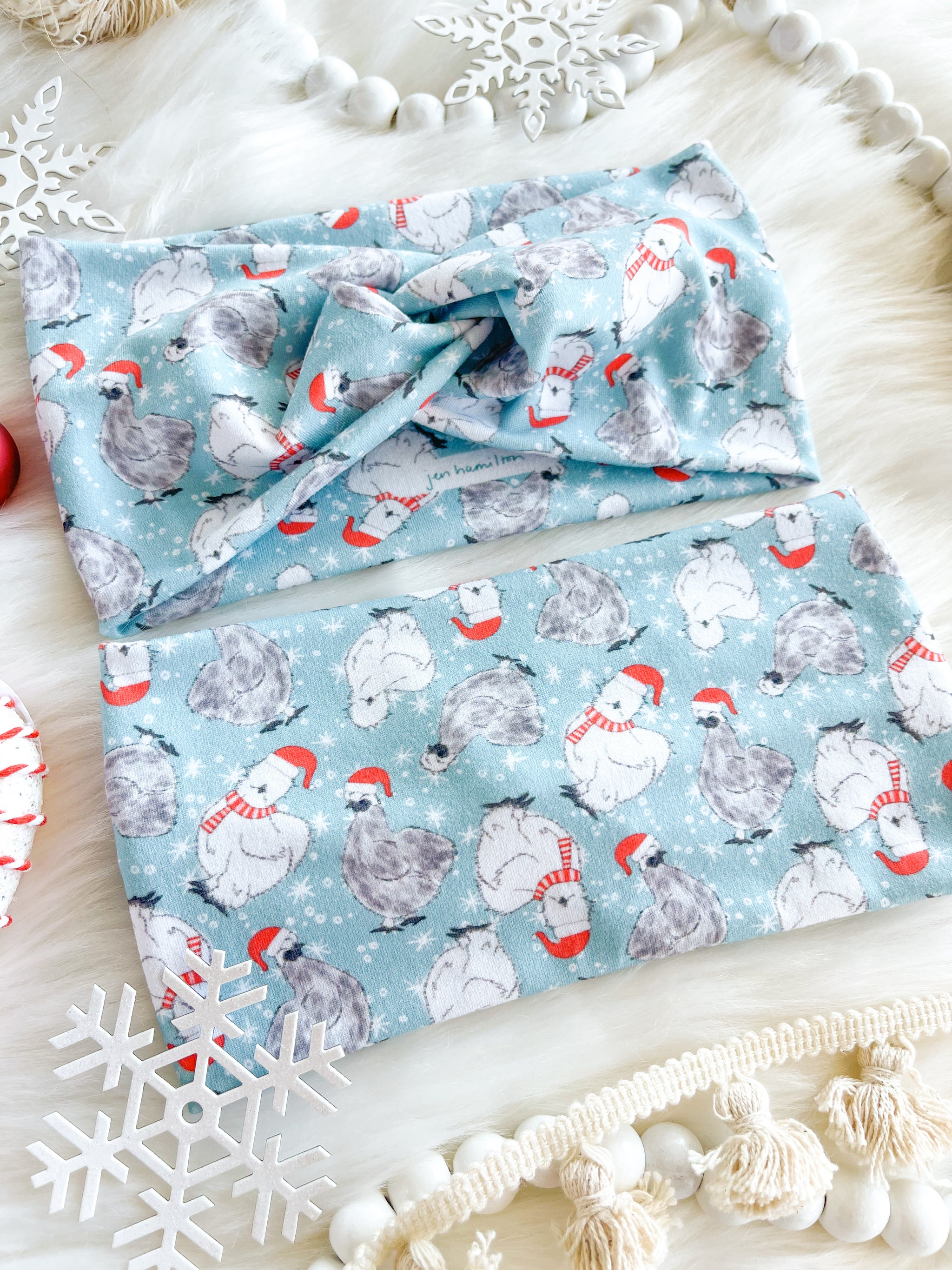 Adult women's light blue headband with white snowflakes and black and white Silkie chickens with red Santa hats and scarves