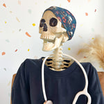 Adult women's black headband with various red, white, blue and green flowers and greenery with shadowed skulls