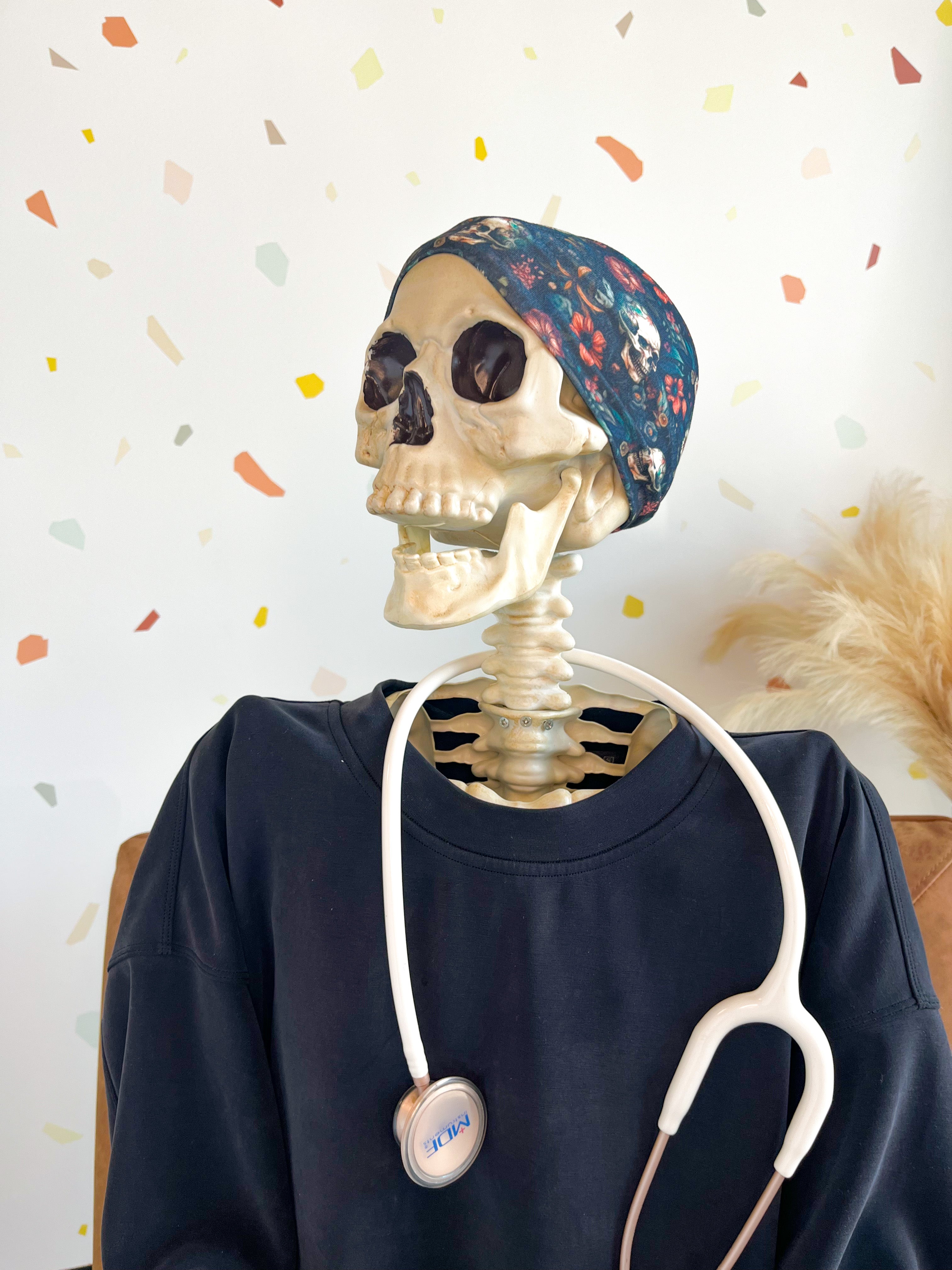 Adult women's black headband with various red, white, blue and green flowers and greenery with shadowed skulls