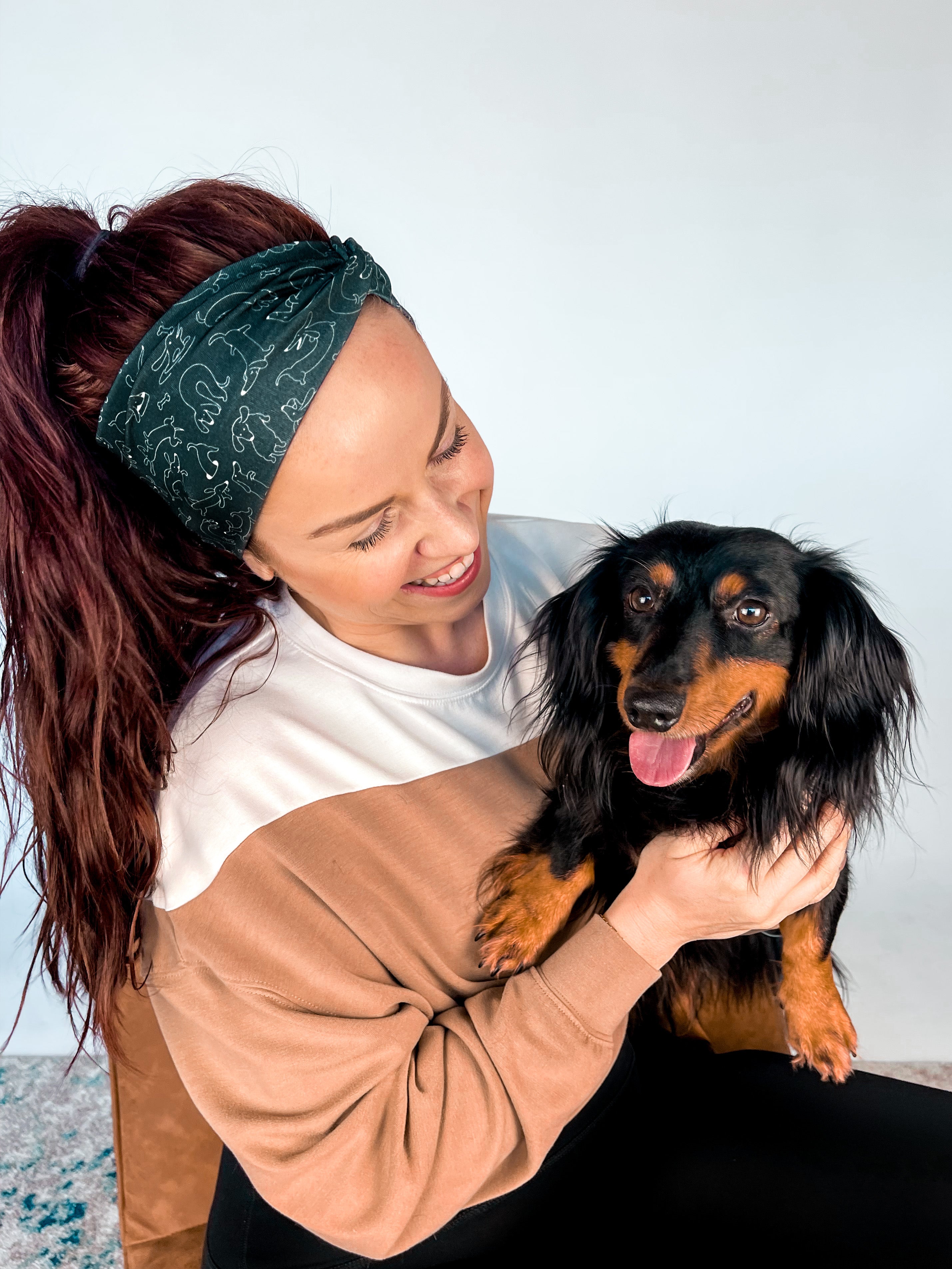 Adult women's black headband with white drawn outline of a playful Dachshund dog