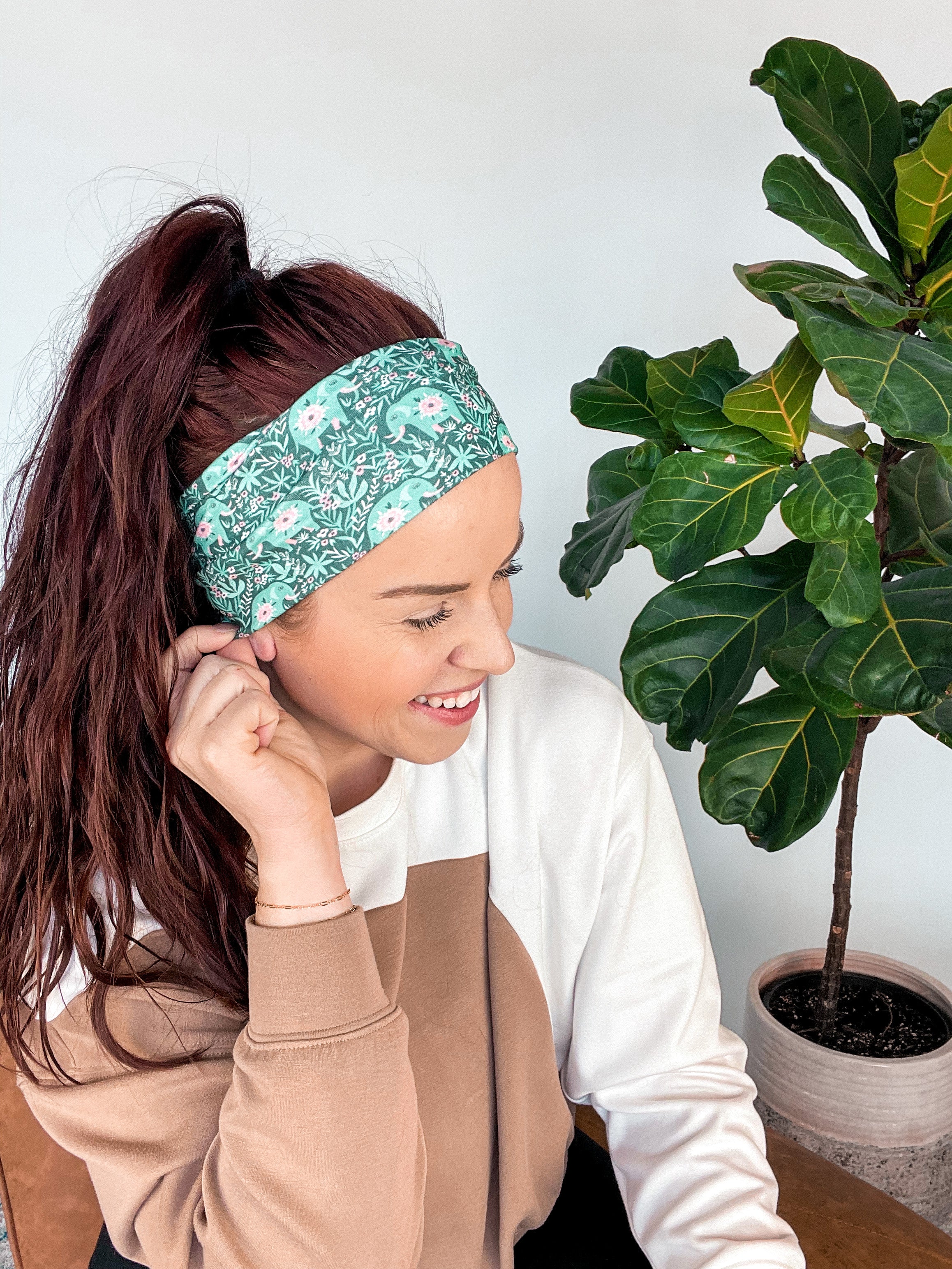 Adult women's dark green headband with teal elephants and greenery, pink tusks and legs and flowers