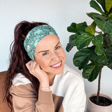 Adult women's dark green headband with teal elephants and greenery, pink tusks and legs and flowers