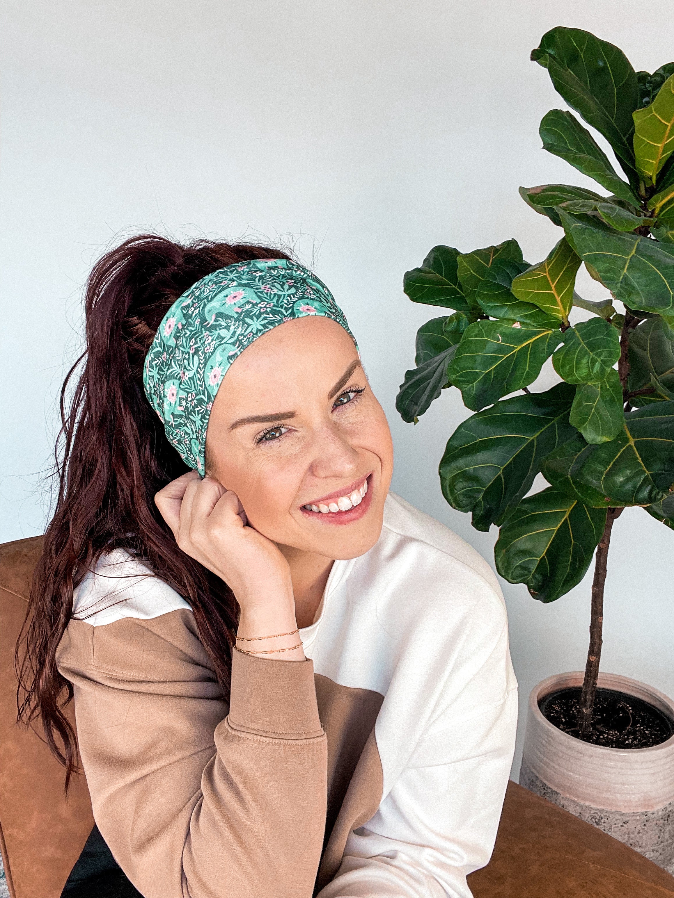 Adult women's dark green headband with teal elephants and greenery, pink tusks and legs and flowers