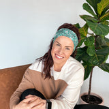 Adult women's dark green headband with teal elephants and greenery, pink tusks and legs and flowers