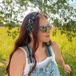 Woman in a field wearing the Feelin' Berry Good headband, sunglasses, and a white tank top with blue overalls, showcasing the headband's stylish functionality.