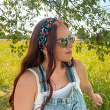 Woman in a field wearing the Feelin' Berry Good headband, sunglasses, and a white tank top with blue overalls, showcasing the headband's stylish functionality.