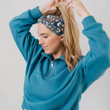 Woman wearing the Science Skunk black headband with artistic black and white skunk and teal, gold, pink and white allover flowers