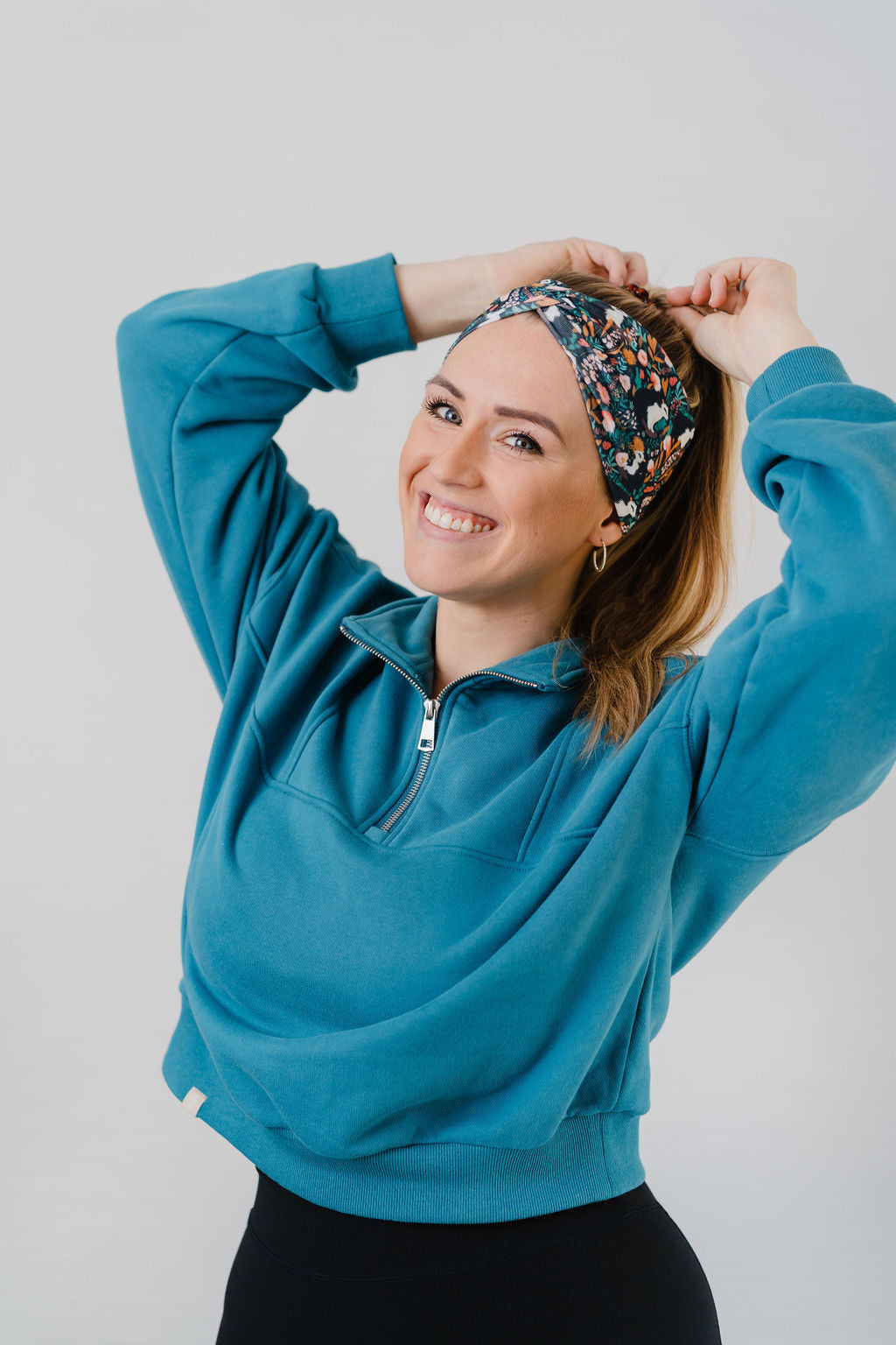 Woman wearing the Science Skunk black headband with artistic black and white skunk and teal, gold, pink and white allover flowers