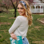 A woman with blonde hair wearing a Uniquely Magic headband, showcasing a versatile 3-in-1 twist style. Functional, machine washable, sweat absorbent, and non-slip for workouts, shifts, or play.