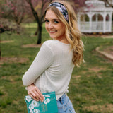 A woman with blonde hair wearing a Uniquely Magic headband, showcasing a versatile 3-in-1 twist style. Functional, machine washable, sweat absorbent, and non-slip for workouts, shifts, or play.