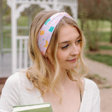 A woman wearing a Book Fairy headband holds books, embodying confidence and functionality. Lilac Market Headbands: versatile, sweat-absorbent, non-slip, perfect for workouts or play. Designed in Springfield, MO.