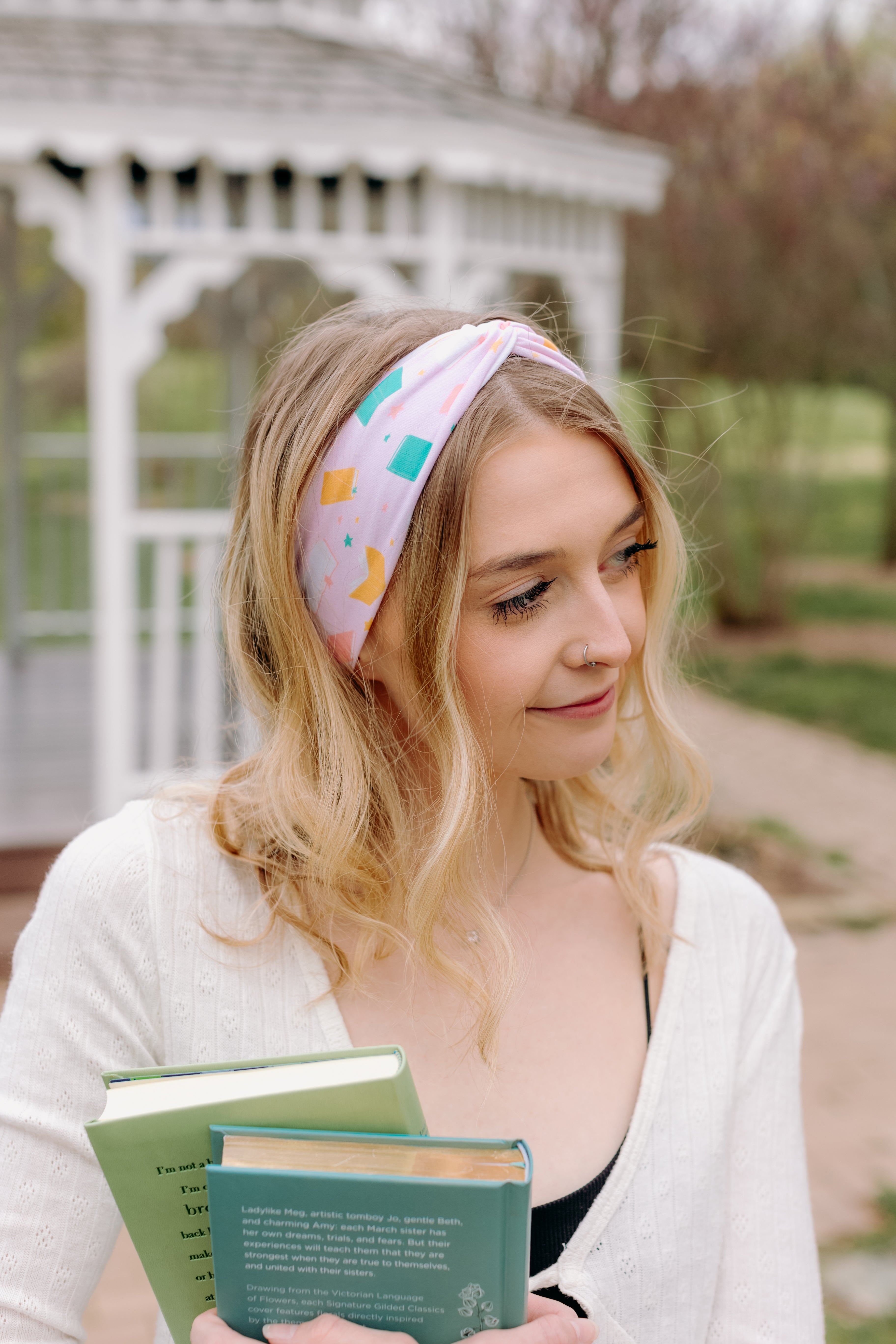 A woman wearing a Book Fairy headband holds books, embodying confidence and functionality. Lilac Market Headbands: versatile, sweat-absorbent, non-slip, perfect for workouts or play. Designed in Springfield, MO.
