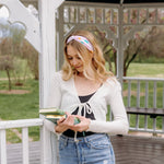 A woman wearing a Book Fairy headband holds books, embodying confidence and functionality. Lilac Market Headbands: versatile, sweat-absorbent, non-slip, perfect for workouts or play. Designed in Springfield, MO.