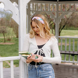 A woman wearing a Book Fairy headband holds books, embodying confidence and functionality. Lilac Market Headbands: versatile, sweat-absorbent, non-slip, perfect for workouts or play. Designed in Springfield, MO.