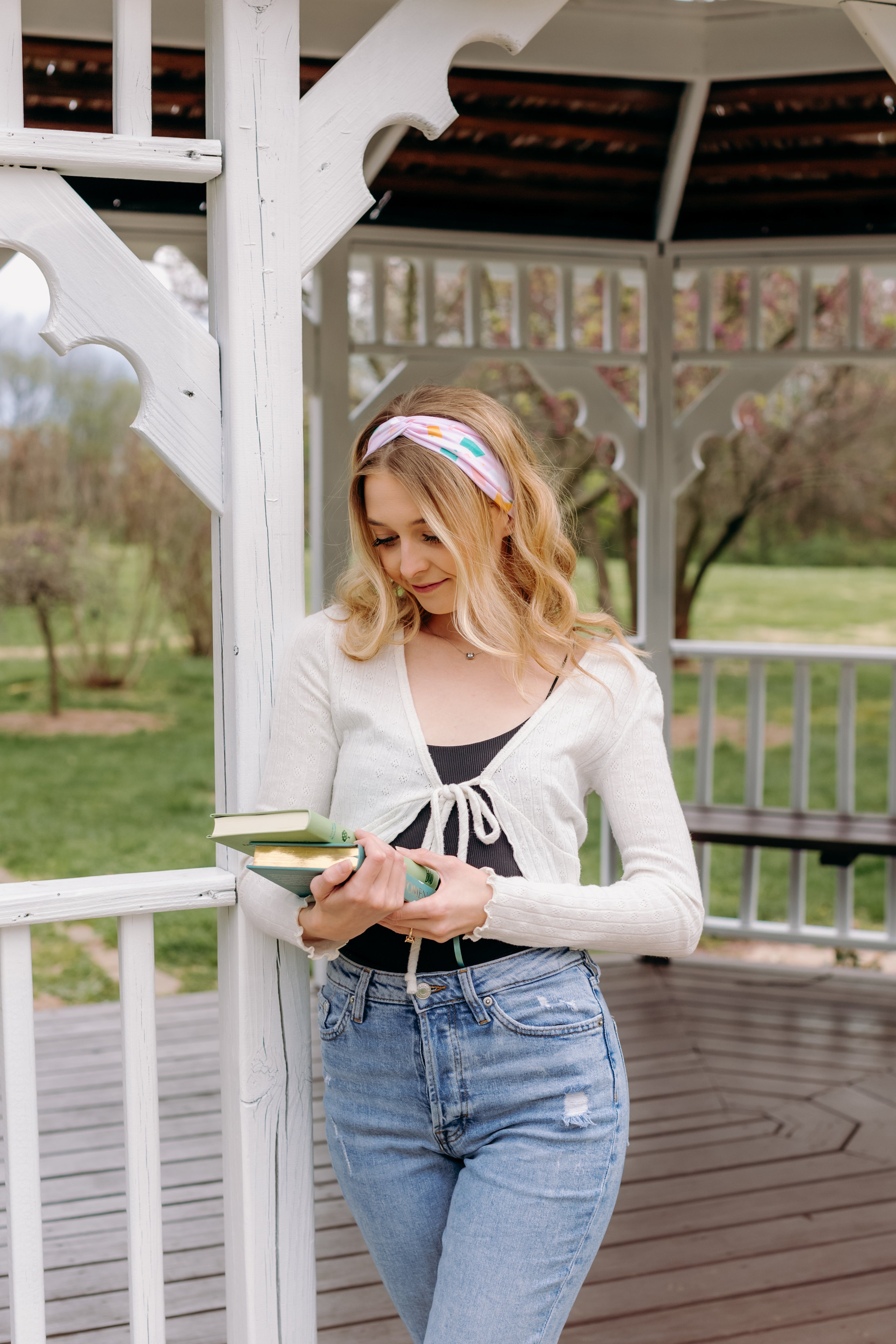 A woman wearing a Book Fairy headband holds books, embodying confidence and functionality. Lilac Market Headbands: versatile, sweat-absorbent, non-slip, perfect for workouts or play. Designed in Springfield, MO.