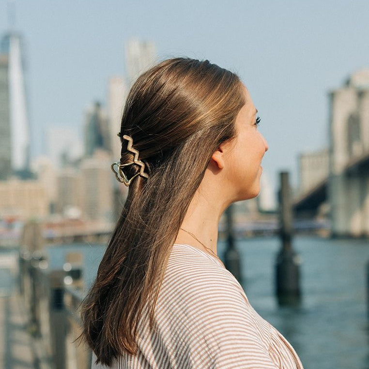 Woman wearing the New York Minute Lilac Clip, a 4.2-inch metal hair accessory from The Sarah Wallace Collection.