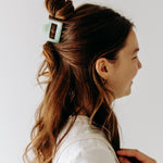 A woman with long hair styled perfectly with the Spring Fling Lilac Clip, showing both fashion and functionality.