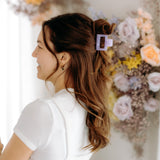 A woman with long hair styled perfectly with the Spring Fling Lilac Clip, showing both fashion and functionality.