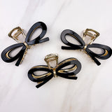 Treat Yourself Lilac Clip, a glossy 4-inch claw clip with hinge closure, available in two color options of white or black, perfect for keeping hair in place.