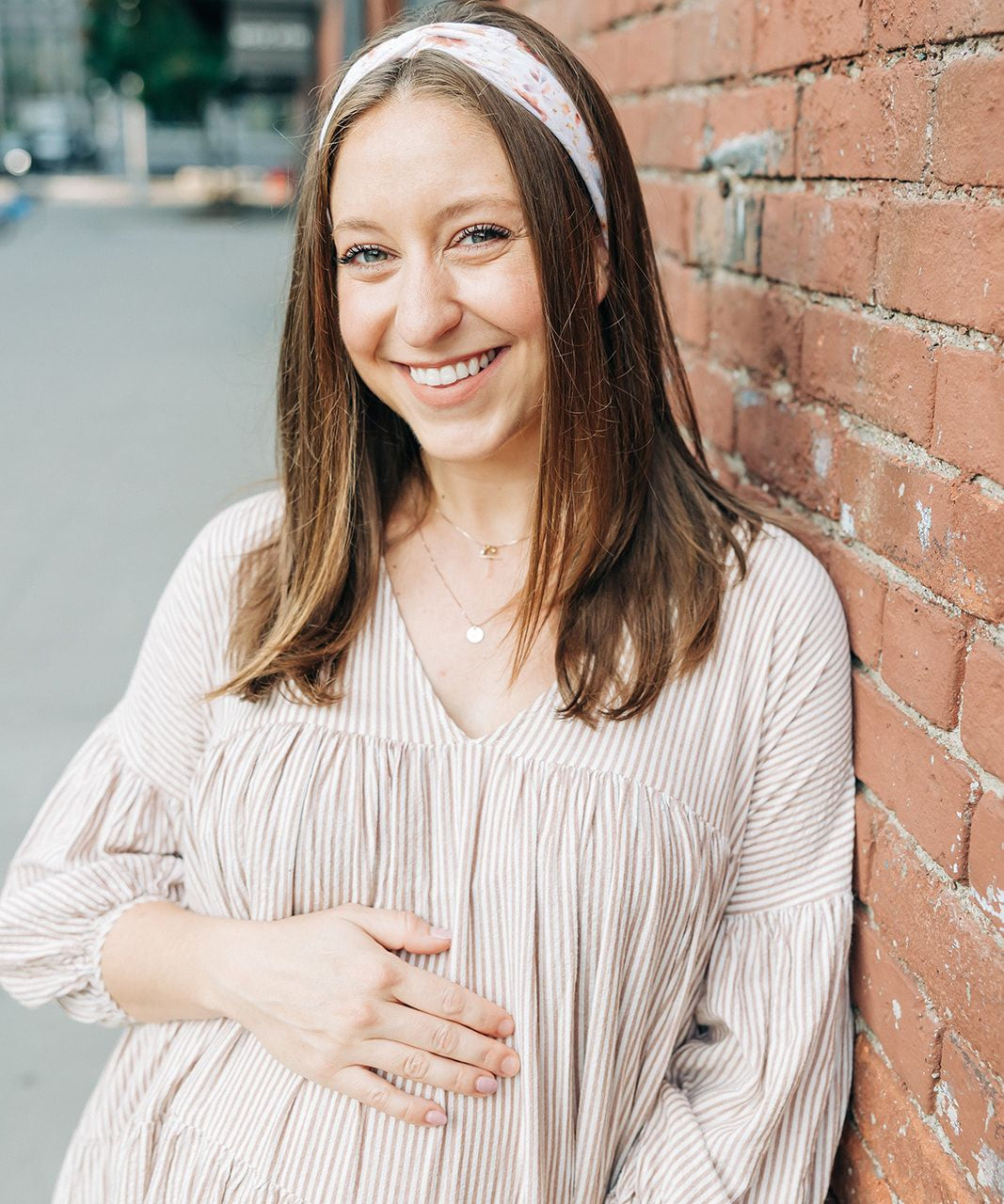 Woman smiling, wearing Preston Floral on Ivory headband from The Sarah Wallace Collection, showcasing its soft, stretchy fabric and versatile 3-in-1 twist style.