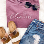 Adult berry colored shirt with Missouri state with the words "Handcrafted with Love in Springfield, MO" over the back, and "Lilac Market in script in the front with the outline of the setting sun