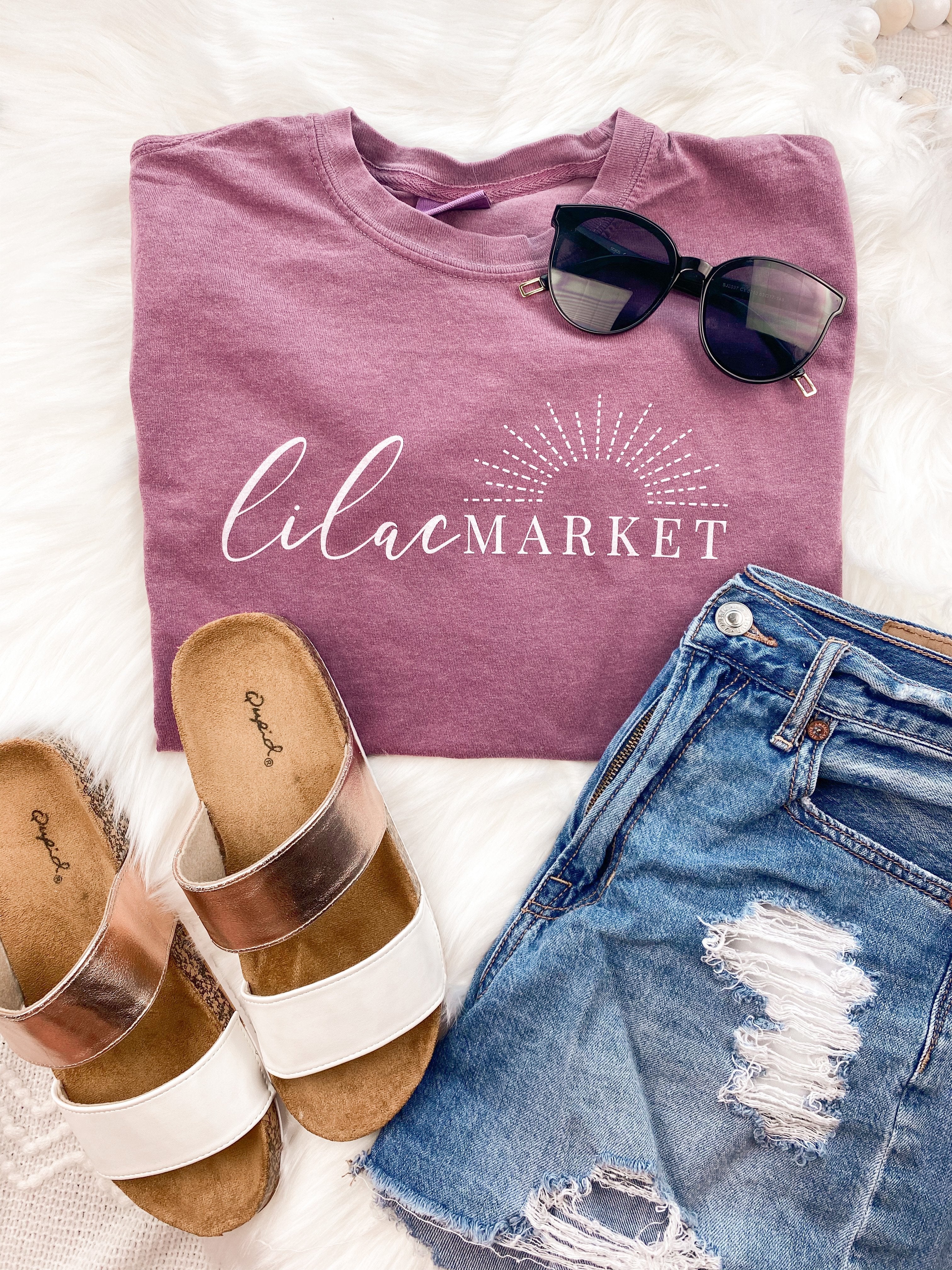 Adult berry colored shirt with Missouri state with the words "Handcrafted with Love in Springfield, MO" over the back, and "Lilac Market in script in the front with the outline of the setting sun