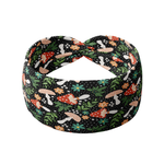Woodland Wonder black headband featuring red and tan spotted mushrooms with flowers and greenery, crafted from a buttery-soft, ultra-stretchy poly-knit blend, designed for reliable non-slip comfort.