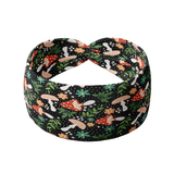 Woodland Wonder black headband featuring red and tan spotted mushrooms with flowers and greenery, crafted from a buttery-soft, ultra-stretchy poly-knit blend, designed for reliable non-slip comfort.