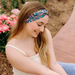A woman in a Courtney Floral on Navy headband, showcasing a versatile 3-in-1 twist style. Designed for confidence and function, machine washable, sweat-absorbent, and non-slip. Sizes for women and children available.