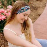 A woman in a Courtney Floral on Navy headband, showcasing a versatile 3-in-1 twist style. Designed for confidence and function, machine washable, sweat-absorbent, and non-slip. Sizes for women and children available.