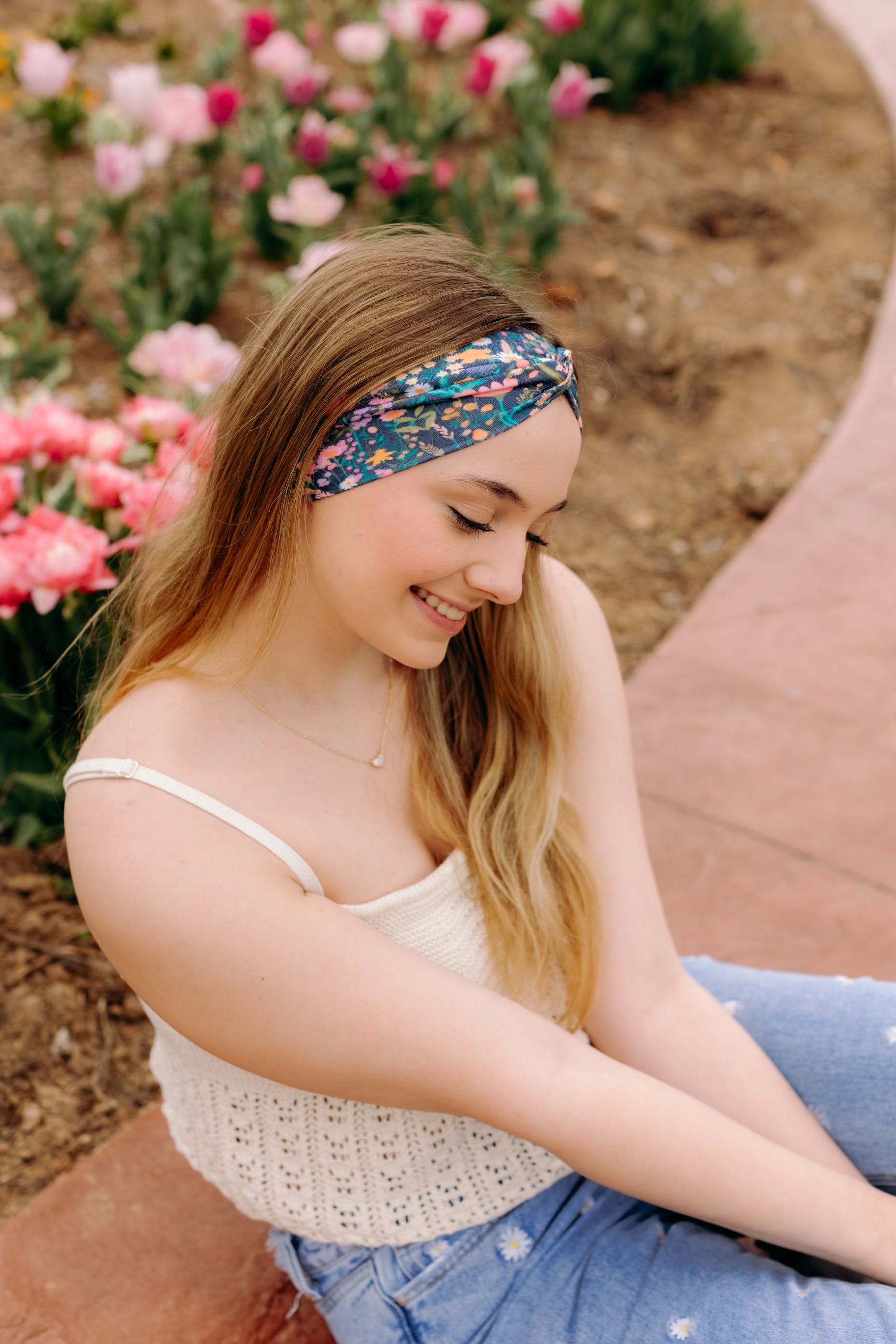 A woman in a Courtney Floral on Navy headband, showcasing a versatile 3-in-1 twist style. Designed for confidence and function, machine washable, sweat-absorbent, and non-slip. Sizes for women and children available.