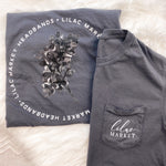Adult grey colored shirt with grey lilac flowers with the words "Lilac Market Headbands" encircling them, and "Lilac Market" script on the front over a small pocket