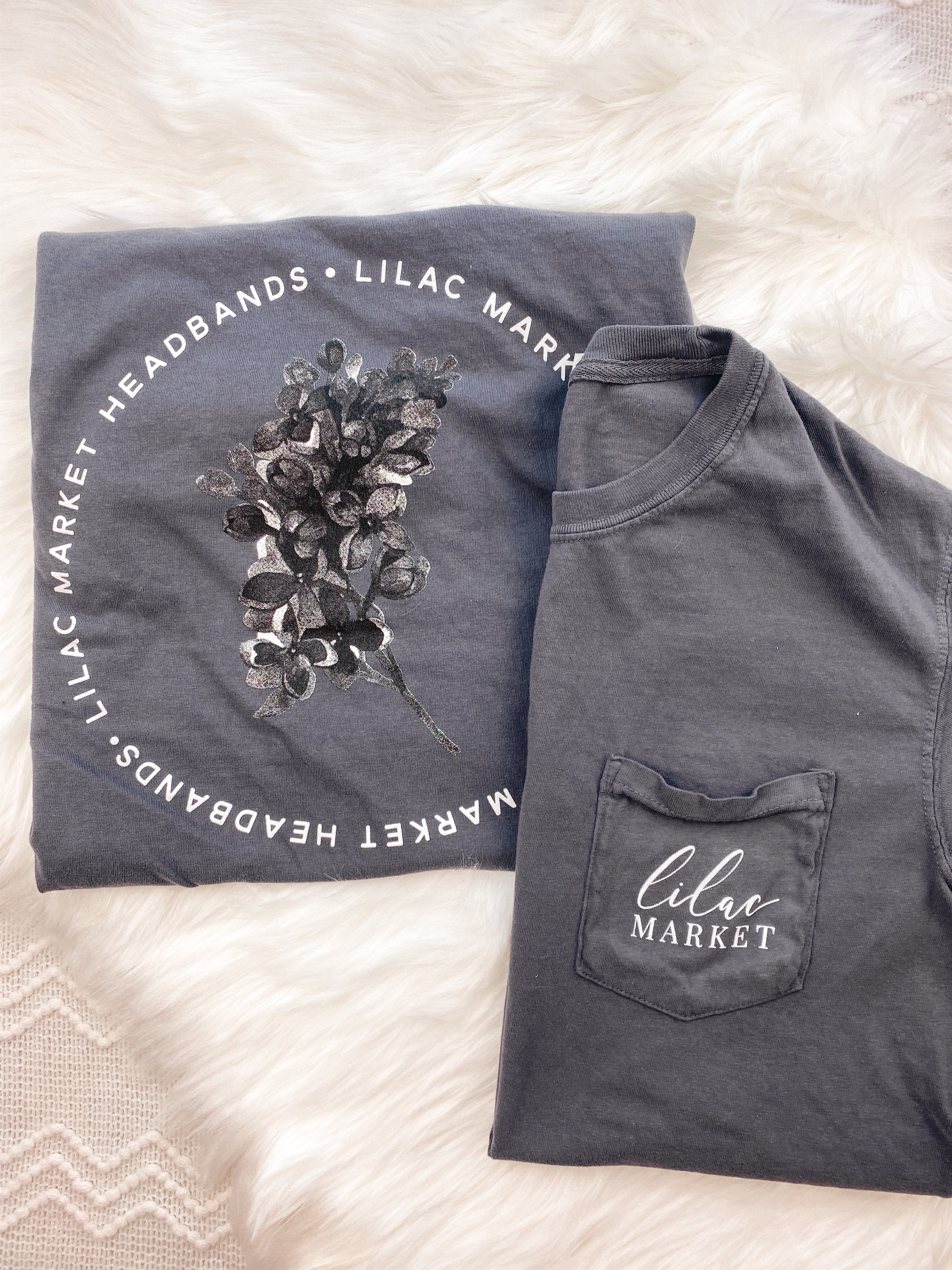 Adult grey colored shirt with grey lilac flowers with the words "Lilac Market Headbands" encircling them, and "Lilac Market" script on the front over a small pocket