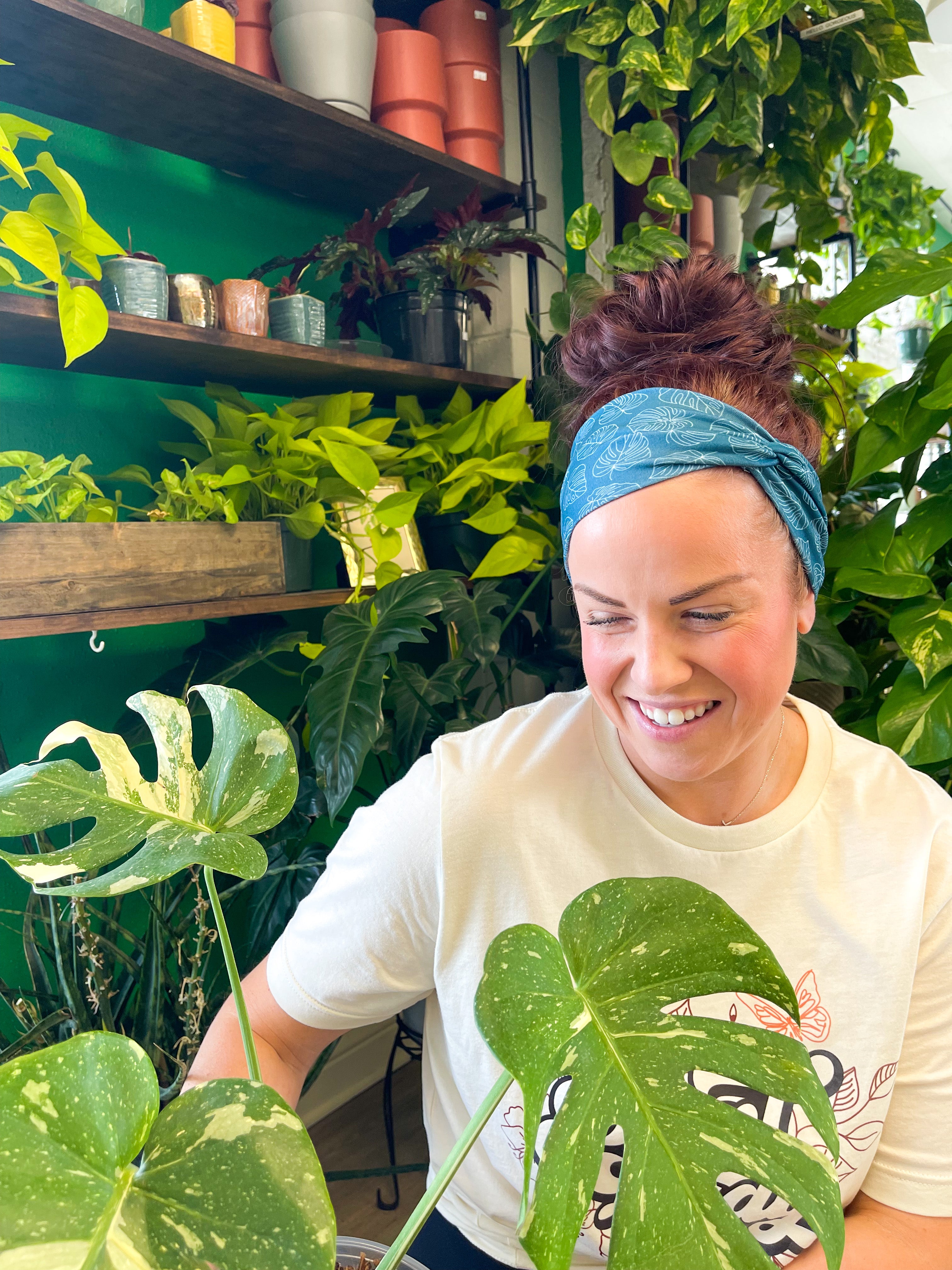 Adult women's dark teal headband with white outline of Monstera plant leaves