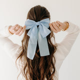 Woman wearing Say Less Lilac Clip with blue bow, a cute fashion accessory.