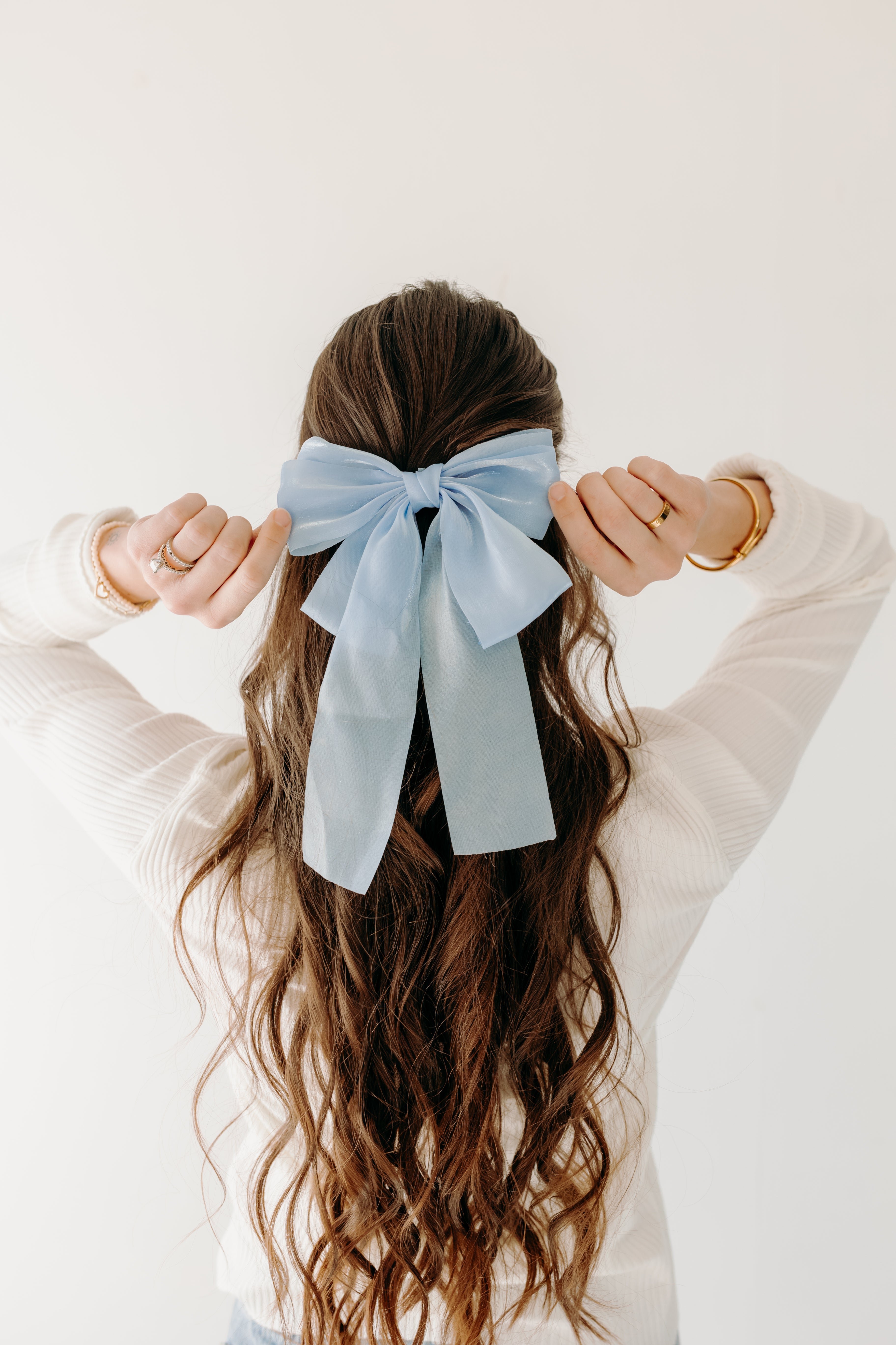 Woman wearing Say Less Lilac Clip with blue bow, a cute fashion accessory.