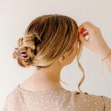 A woman with long hair wearing the Karma Lilac Clip, a hair accessory holding her hair in a twisted bun.