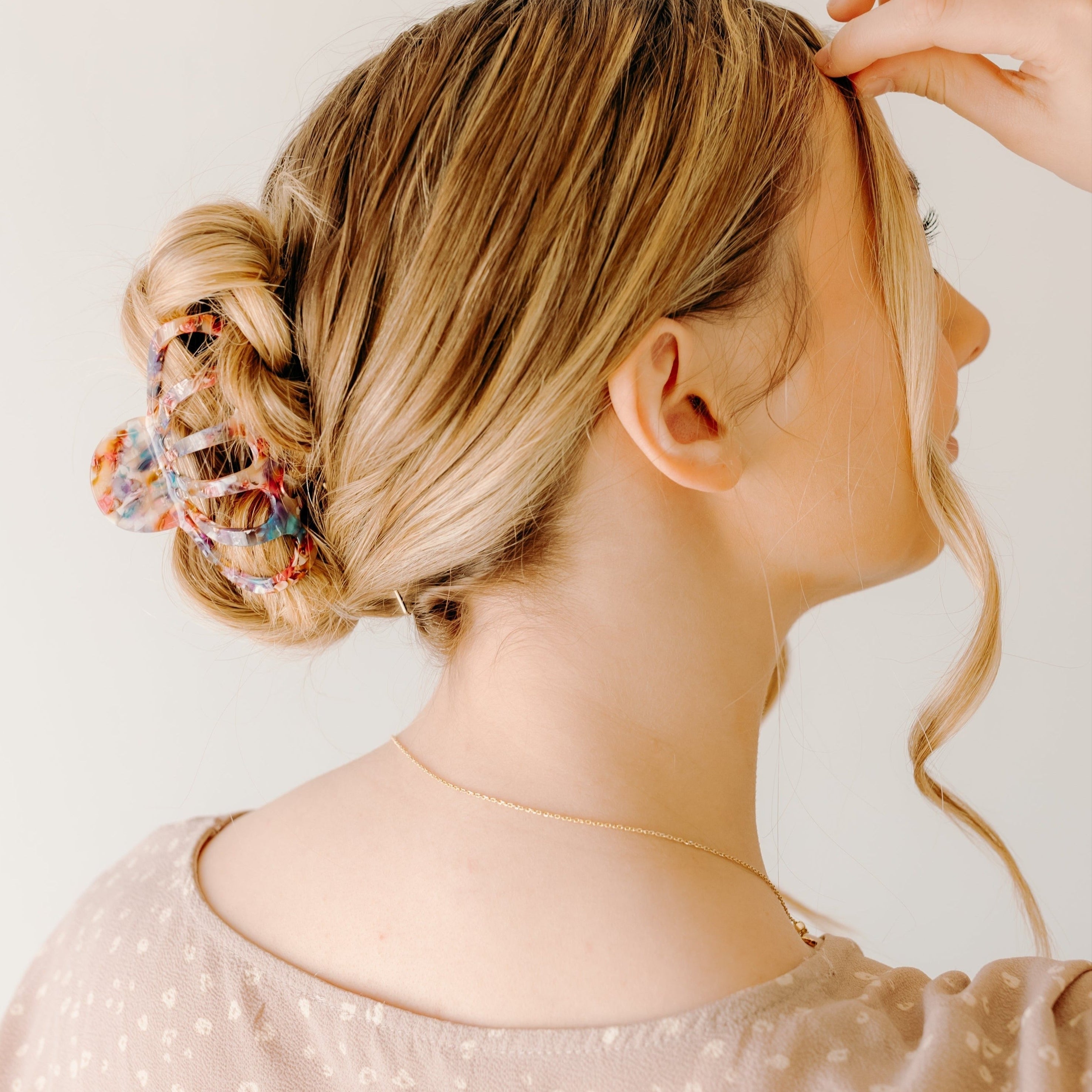 A woman with long hair wearing the Karma Lilac Clip, a hair accessory holding her hair in a twisted bun.