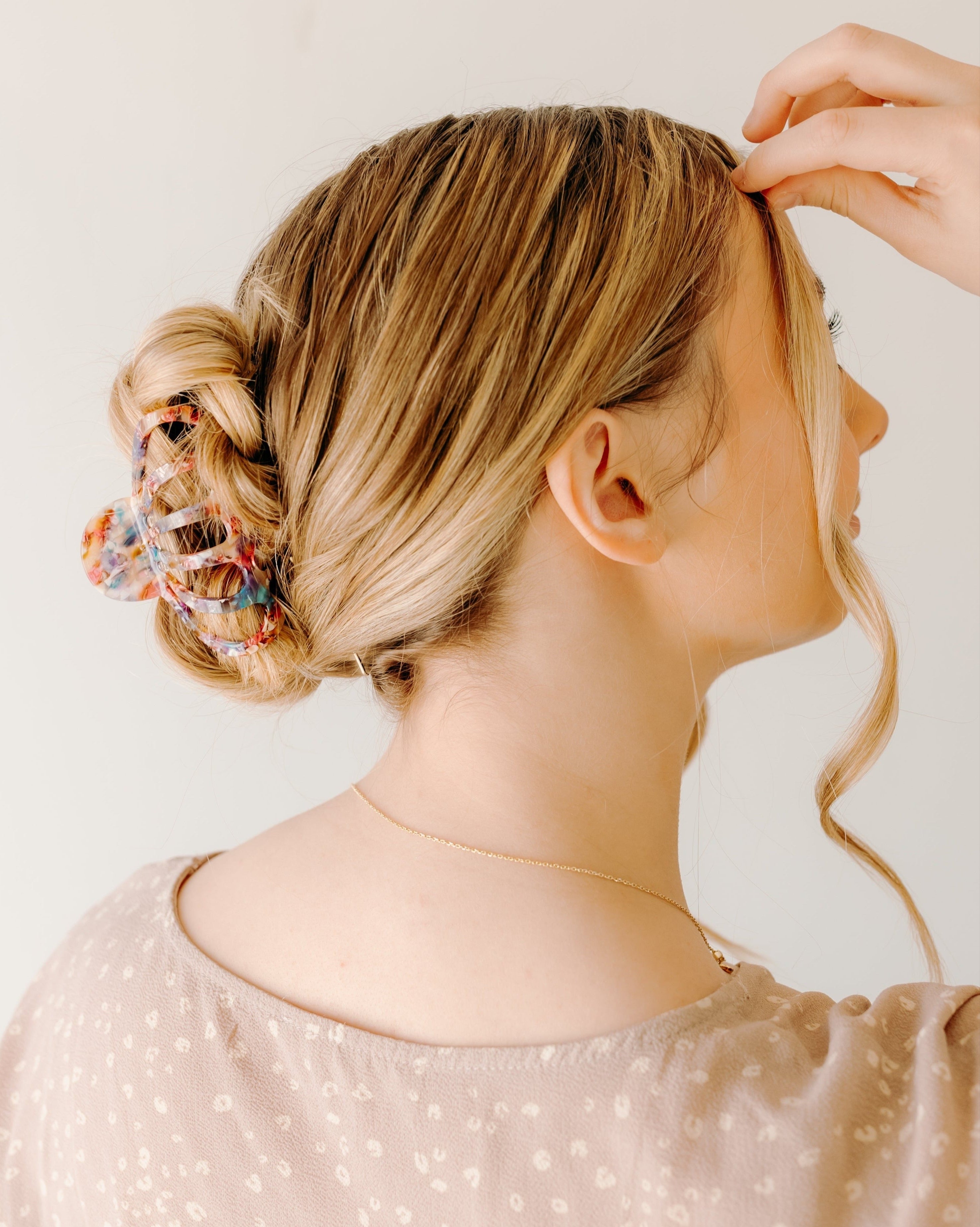 A woman with long hair wearing the Karma Lilac Clip, a hair accessory holding her hair in a twisted bun.