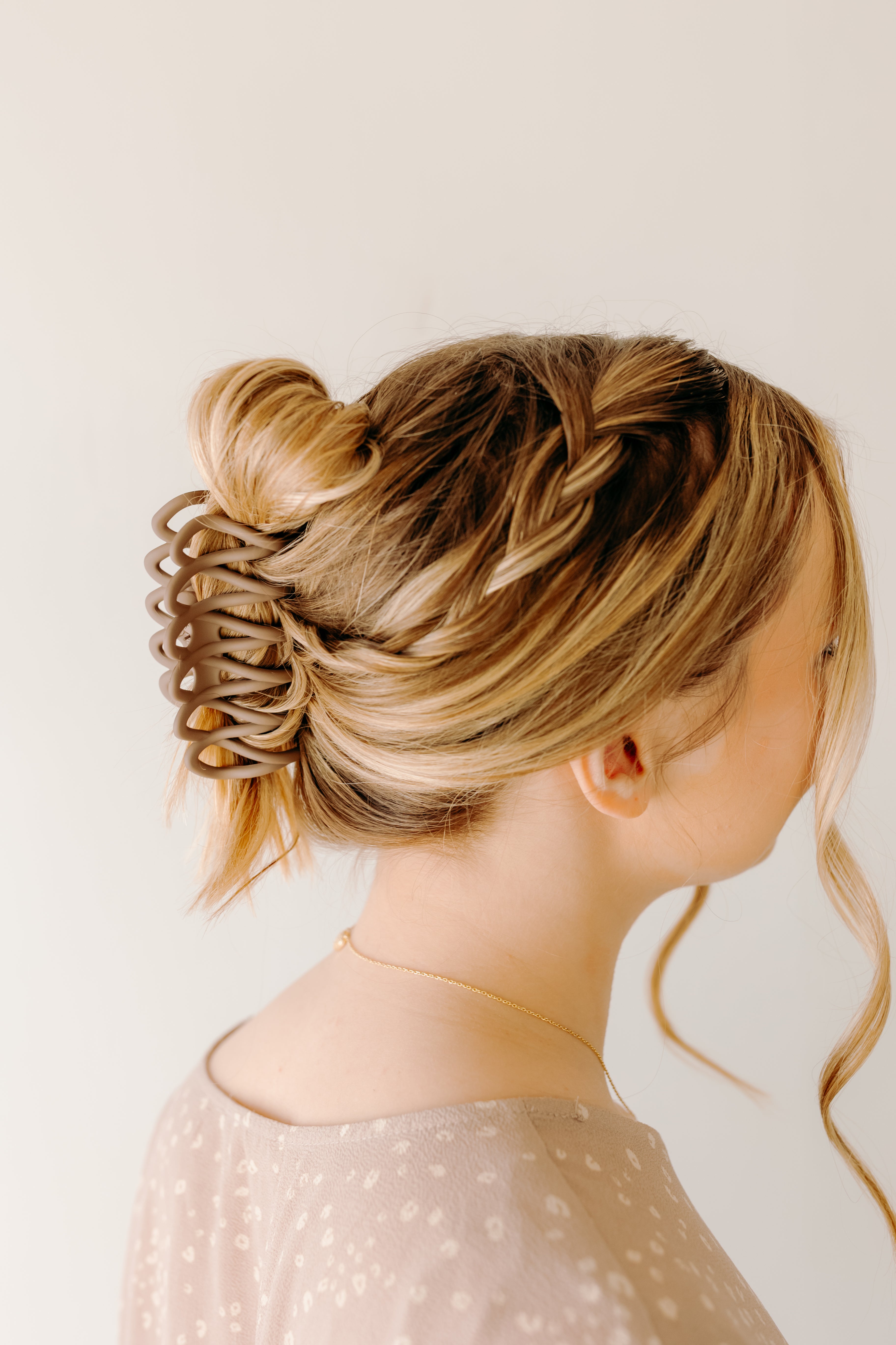 Woman wearing the mocha Take It Easy Lilac Clip, hair styled in a twisted bun with the clip.