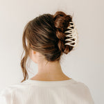 Woman wearing the ivory Take It Easy Lilac Clip, hair styled in a twisted bun with the clip.