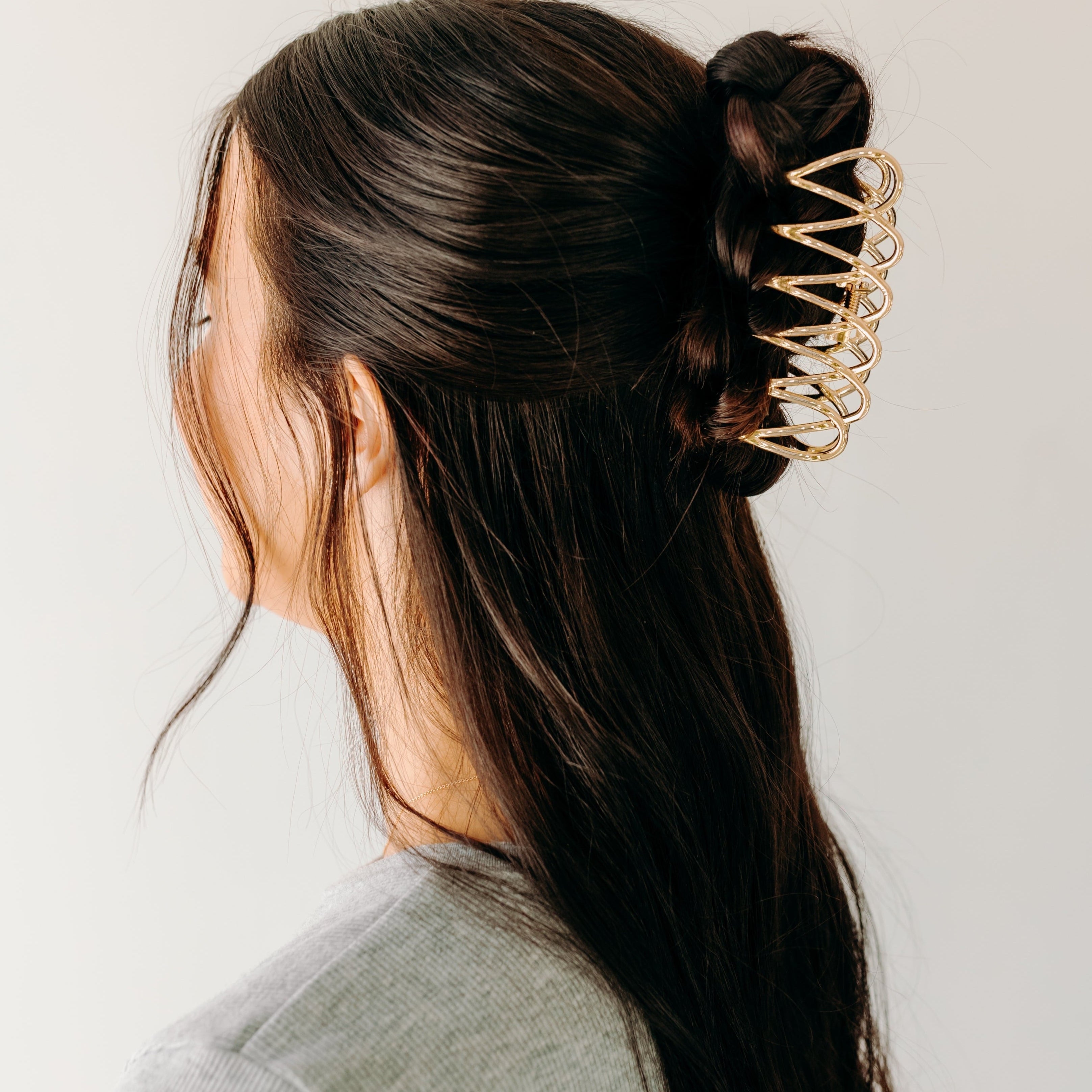 A woman wearing a gold Out Of Office Lilac clip, showcasing the half-up hairstyle. 3.6 inches long, shiny gold metal, perfect for all hair types. Hinge closure for a secure fit.