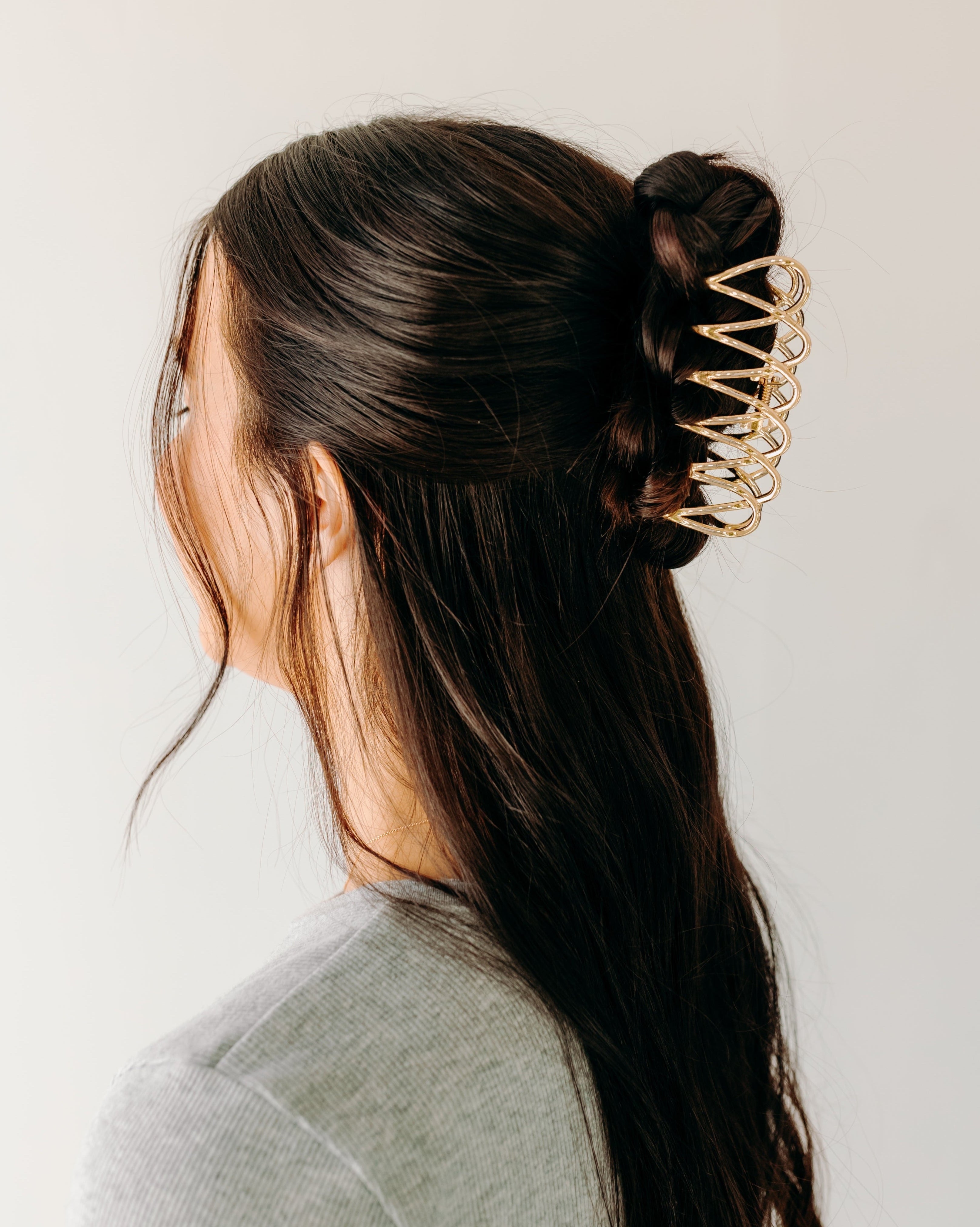 A woman wearing a gold Out Of Office Lilac clip, showcasing the half-up hairstyle. 3.6 inches long, shiny gold metal, perfect for all hair types. Hinge closure for a secure fit.