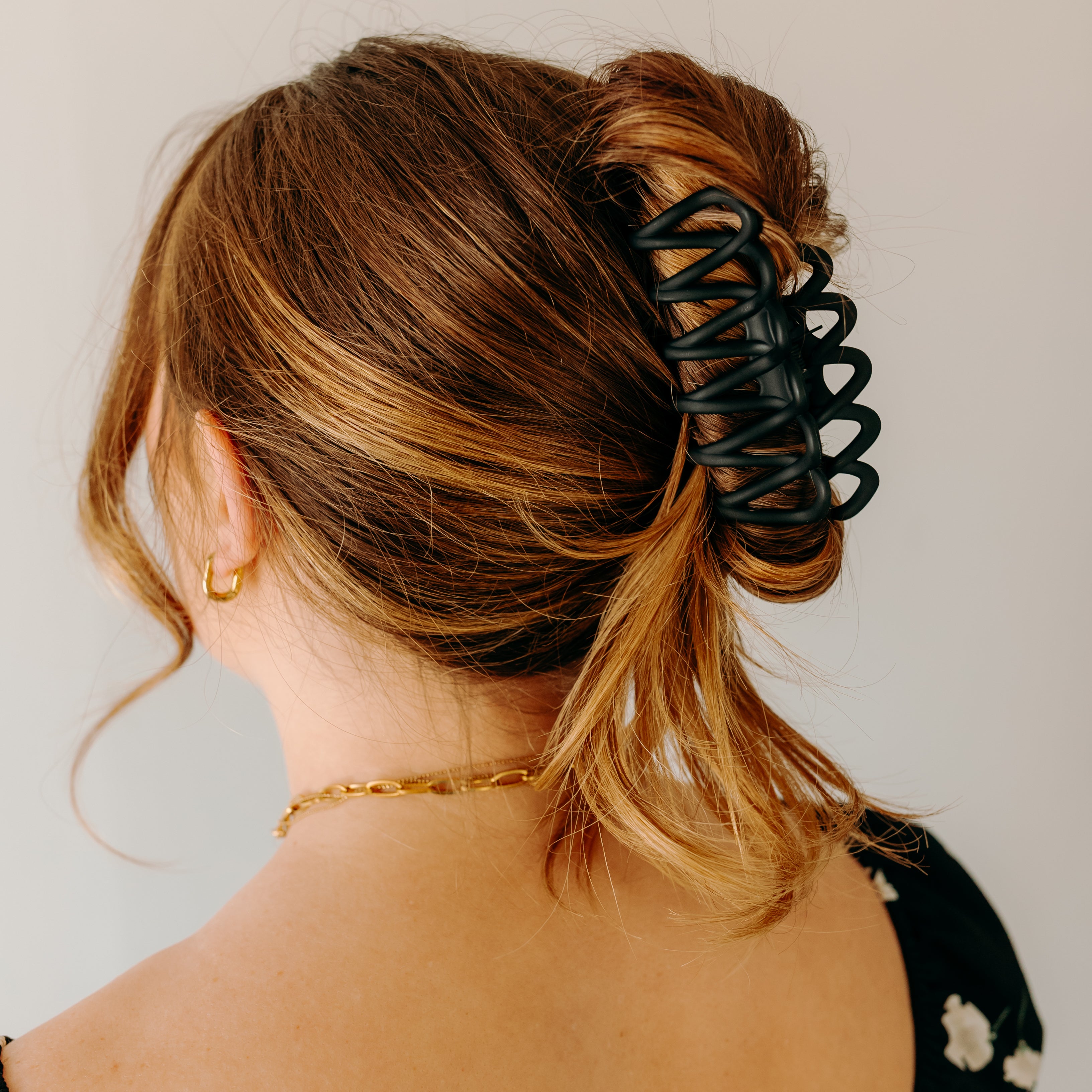 Woman wearing the black Take It Easy Lilac Clip, hair styled in a twisted bun with the clip.