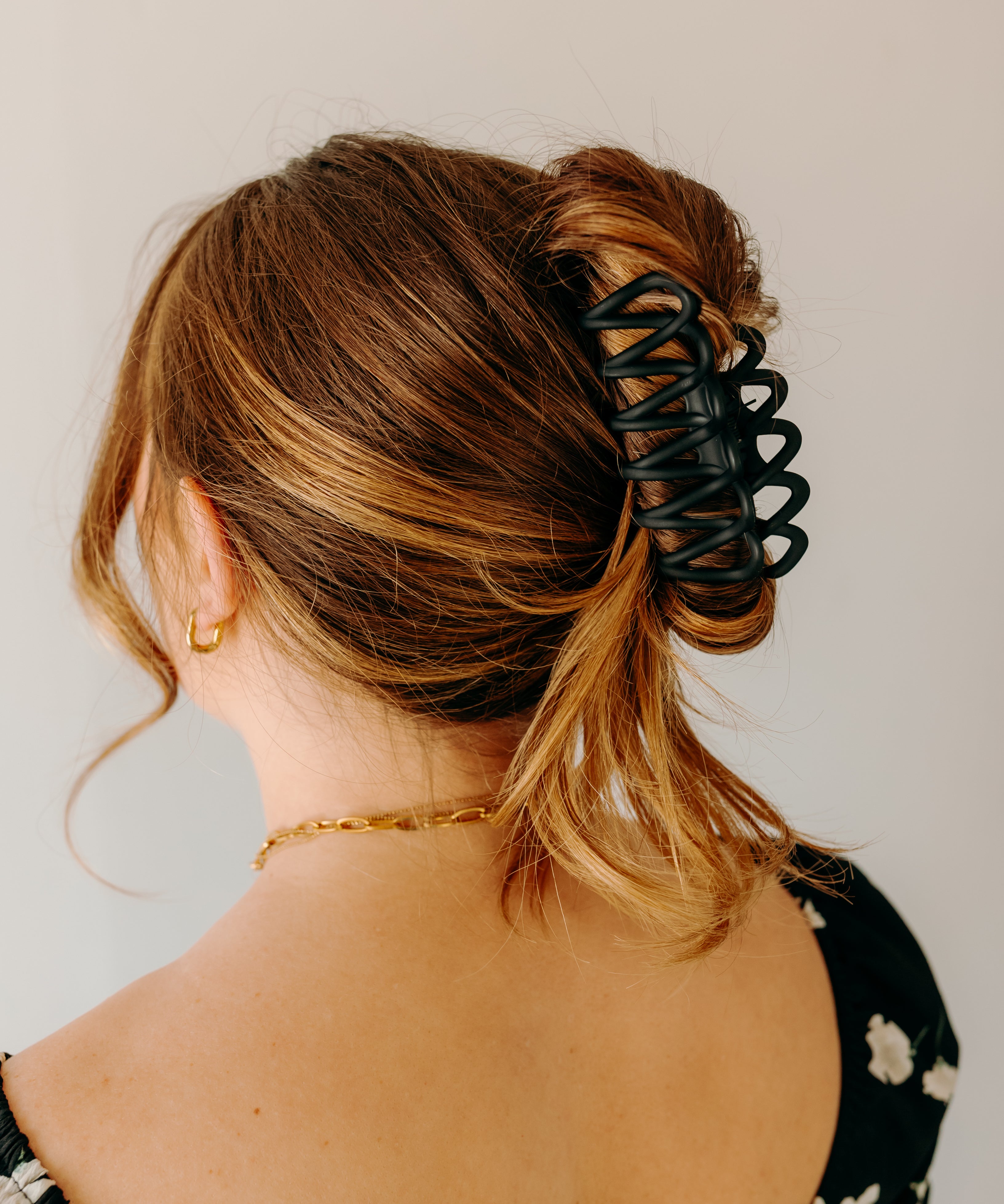 Woman wearing the black Take It Easy Lilac Clip, hair styled in a twisted bun with the clip.