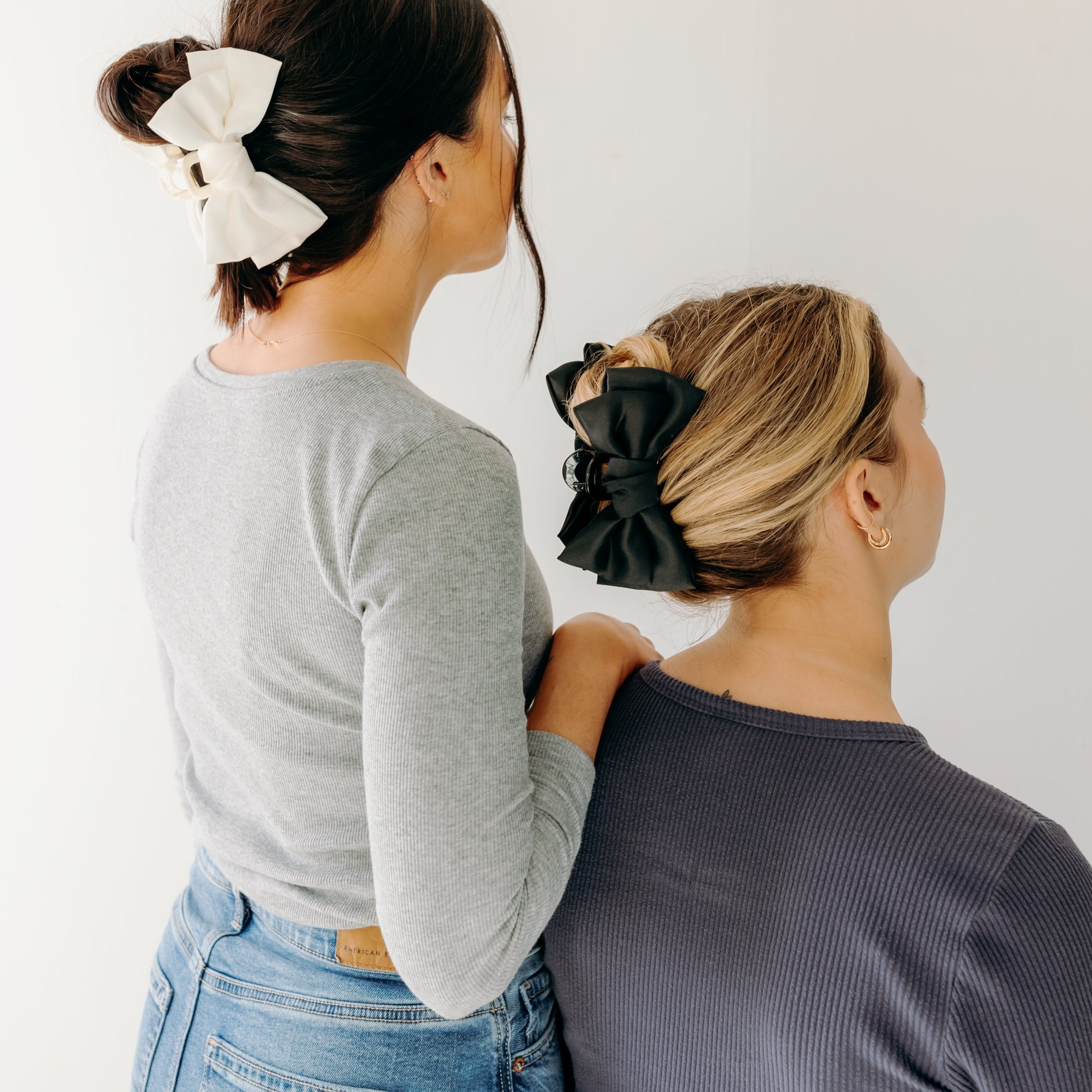 Two women wearing the Classy Chic Lilac Clips in their hair with bows.