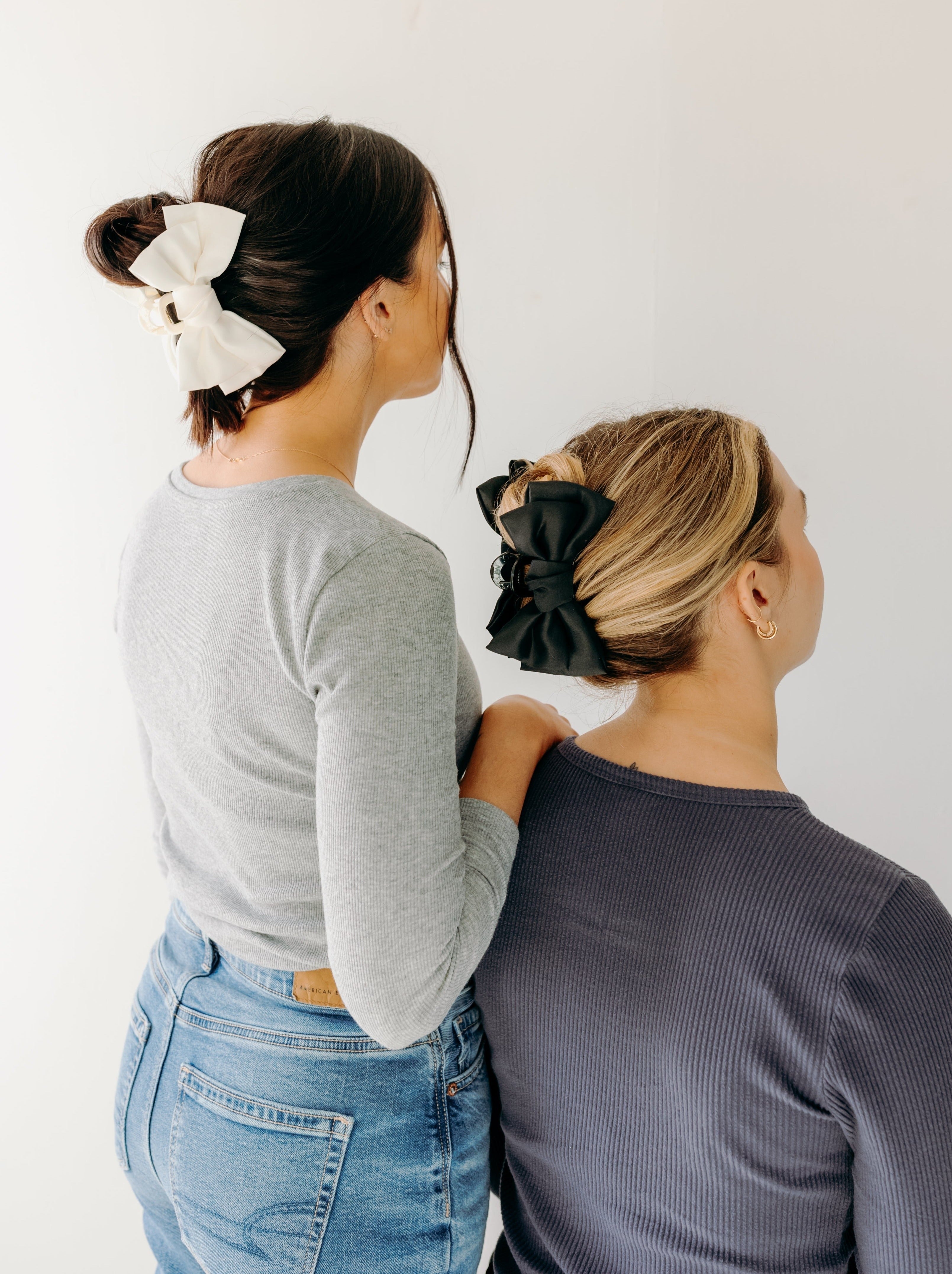 Two women wearing the Classy Chic Lilac Clips in their hair with bows.