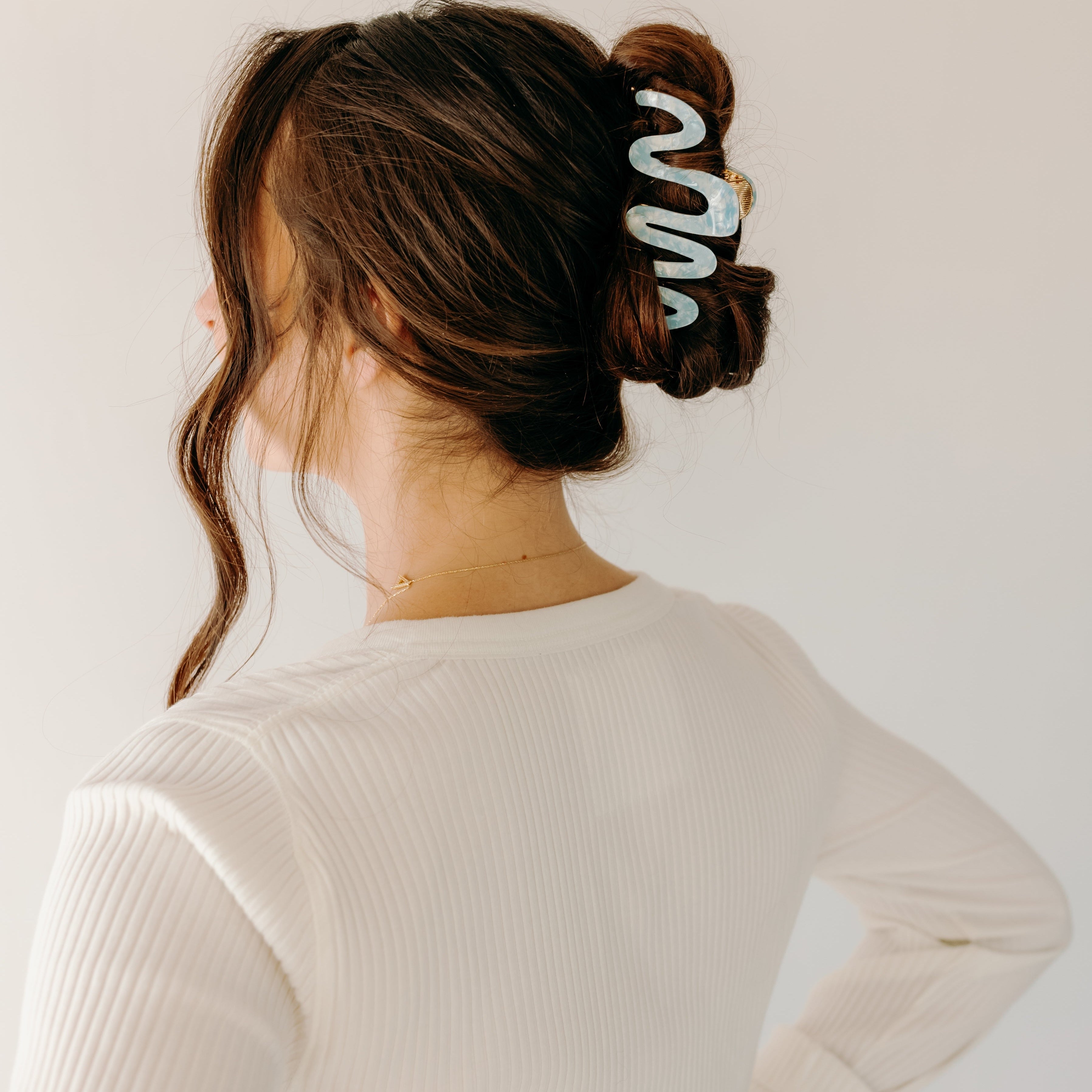 Woman wearing a light blue Comes in Waves Lilac Clip hair clip, showcasing her hairstyle.